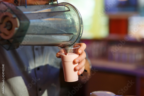 The hand of the bartender  pours the milkshake
