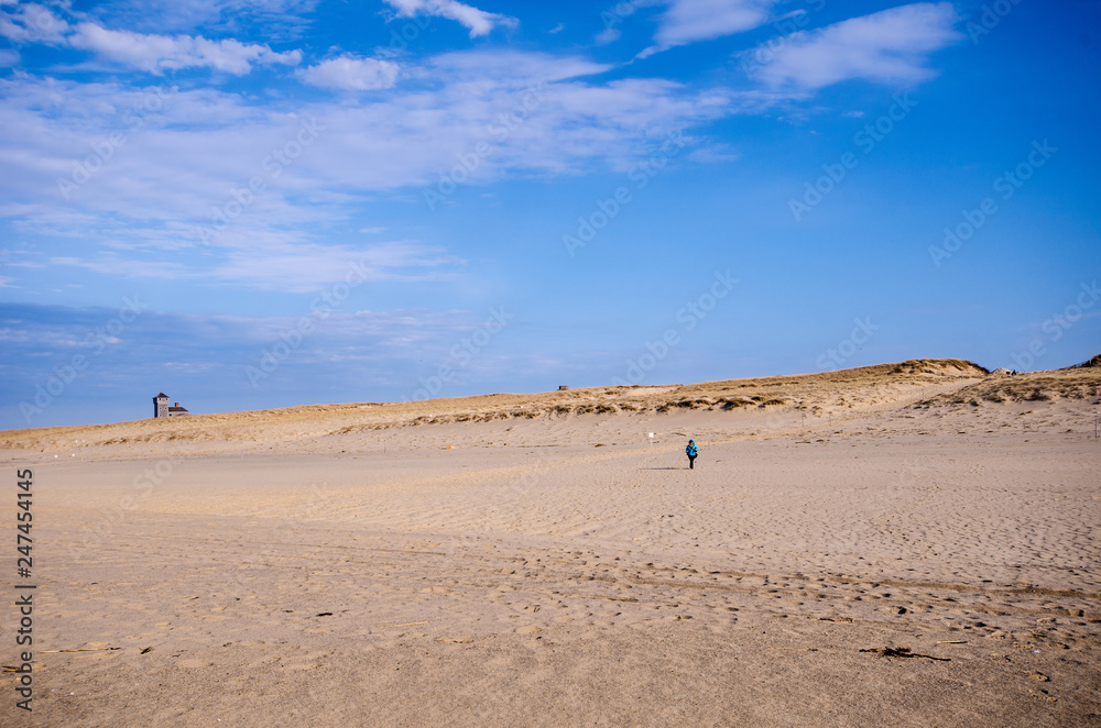 Lone woman hiker on the beach, walks alone in the sand on Cape Cod National Seashore in Provincetown Lone woman hiker on the beach, walks alone in the sand on Cape Cod National Seashore in Provincetown