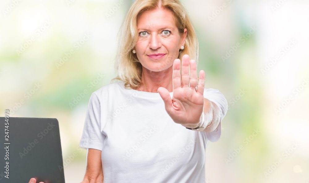 Middle age blonde woman using computer laptop over isolated background with open hand doing stop sign with serious and confident expression, defense gesture Middle age blonde woman using computer laptop over isolated background with open hand doing stop sign with serious and confident expression, defense gesture