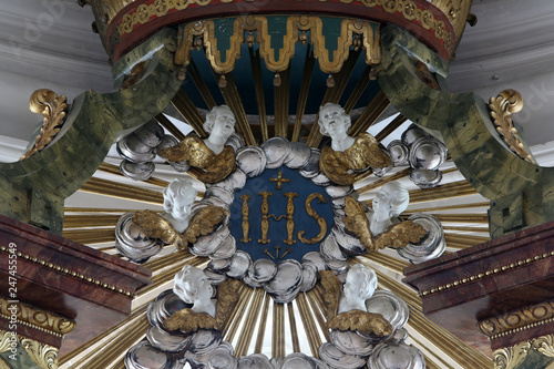 IHS sign (Christogram) above church altar,  Basilica of St. Vitus in Ellwangen, Germany photo