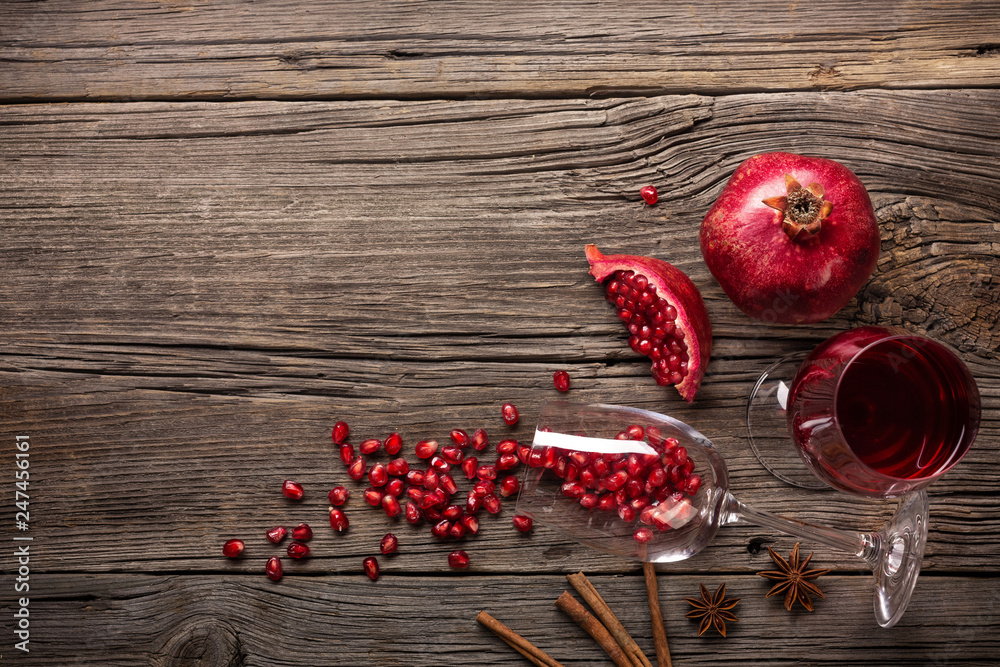Ripe pomegranate fruit with a glass of wine and a corkscrew on a wooden background Ripe pomegranate fruit with a glass of wine and a corkscrew on a wooden background