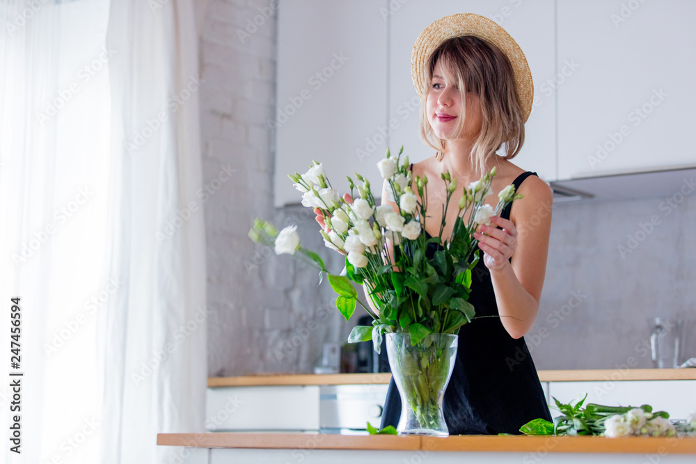 a girl dressed in a black dress near white roses bouquet in a vase. Spring time concept