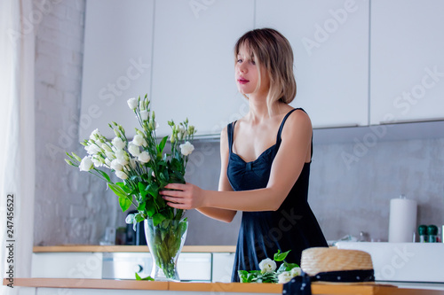 a girl dressed in a black dress is holding white roses in a bouquet before putting them in a vase. Sprint time concept