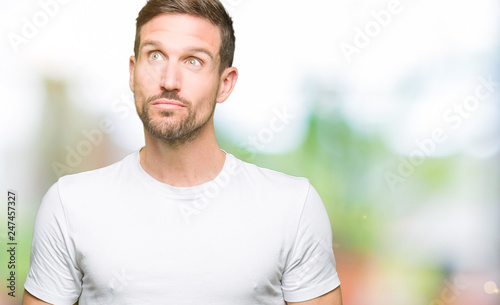 Handsome man wearing casual white t-shirt smiling looking side and staring away thinking.