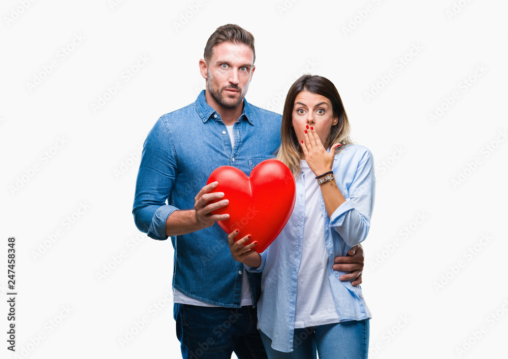 Young couple in love holding red heart over isolated background cover mouth with hand shocked with shame for mistake, expression of fear, scared in silence, secret concept Young couple in love holding red heart over isolated background cover mouth with hand shocked with shame for mistake, expression of fear, scared in silence, secret concept