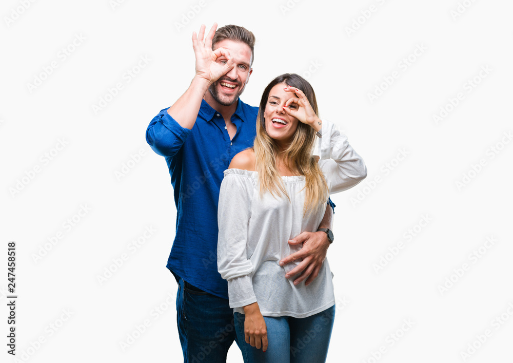 Young couple in love over isolated background doing ok gesture with hand smiling, eye looking through fingers with happy face. Young couple in love over isolated background doing ok gesture with hand smiling, eye looking through fingers with happy face.