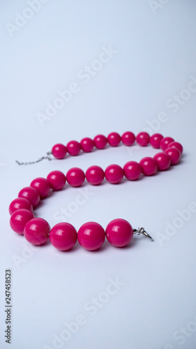 Pink beads on a white background. Accessories. Bijouterie. Vertical photography