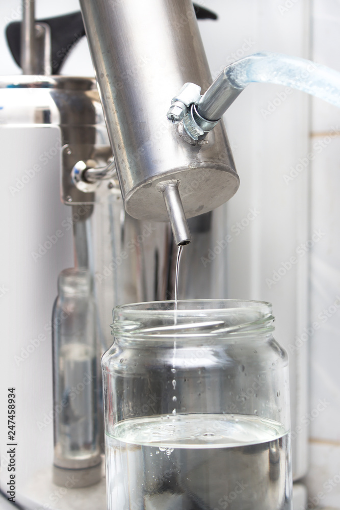 Aparatura do wyrobu alkoholu podczas produkcji alkoholu. Alkohol leci ciurkiem z chłodnicy do słoika. Aparatura do wyrobu alkoholu podczas produkcji alkoholu. Alkohol leci ciurkiem z chłodnicy do słoika.