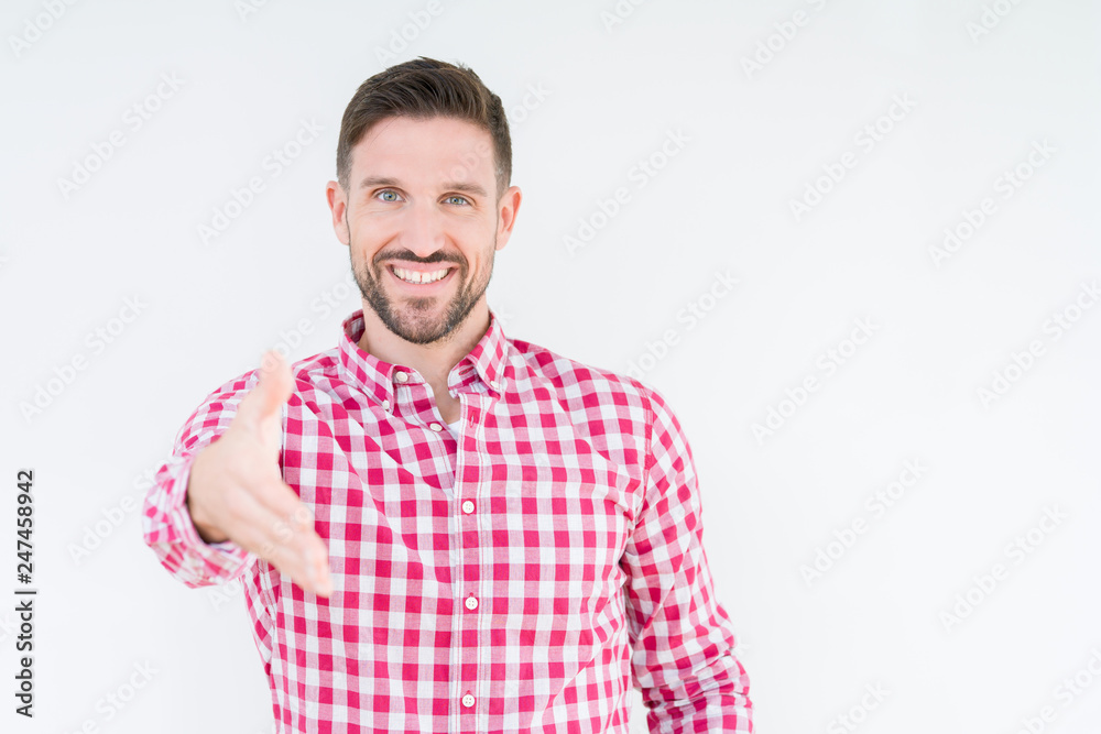 Young handsome man wearing shirt over isolated background smiling friendly offering handshake as greeting and welcoming. Successful business. Young handsome man wearing shirt over isolated background smiling friendly offering handshake as greeting and welcoming. Successful business.