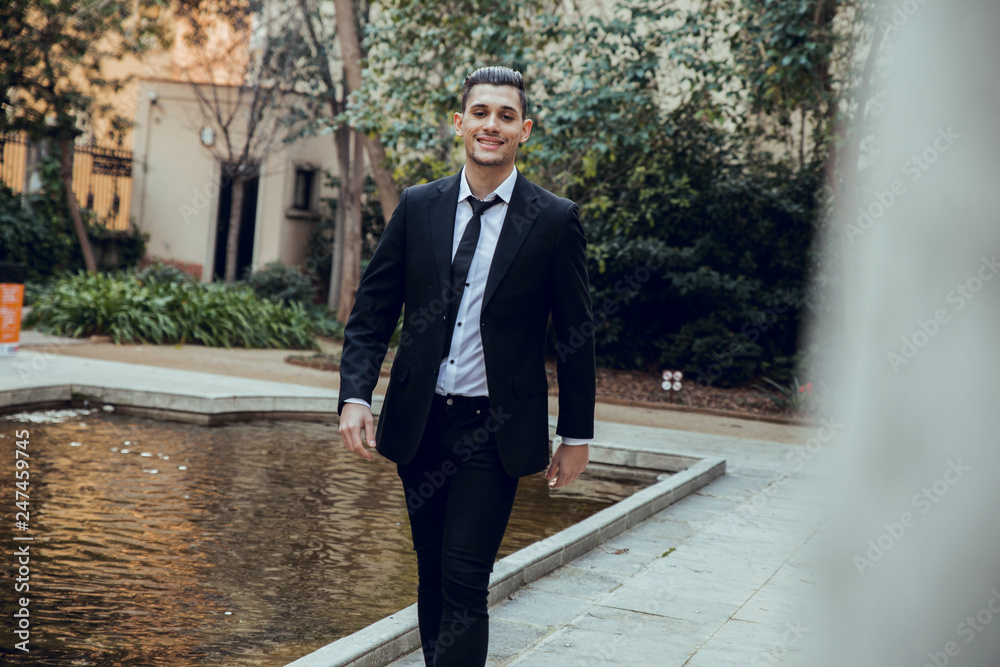 Man with suit walking in park beside lake in Barcelona Man with suit walking in park beside lake in Barcelona