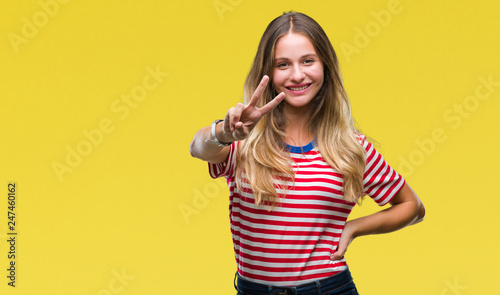 Young beautiful blonde woman over isolated background smiling looking to the camera showing fingers doing victory sign. Number two.