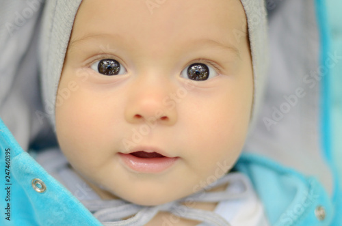 Five month old pretty baby lying on a play mat in the forestand watching at trees reflected in his dark eyes photo