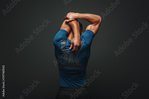 Even if you don't have time for a big workout, stretching in the morning and night really changes your body. Sportsman is stretching standing over dark background photo