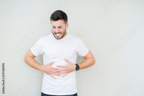 Young handsome man wearing casual white t-shirt over isolated background with hand on stomach because indigestion, painful illness feeling unwell. Ache concept.
