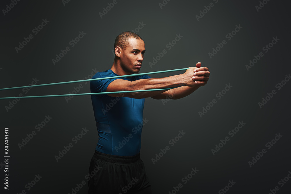Get stronger every day. Sportsman working out with resistance band over  dark background Stock Photo