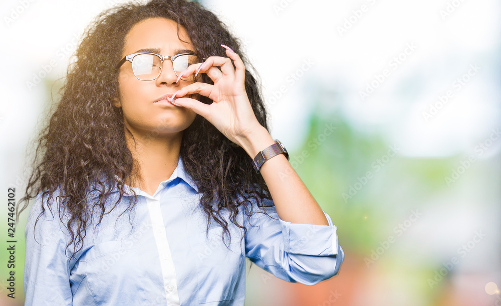 Young beautiful business girl with curly hair wearing glasses mouth and lips shut as zip with fingers. Secret and silent, taboo talking Young beautiful business girl with curly hair wearing glasses mouth and lips shut as zip with fingers. Secret and silent, taboo talking