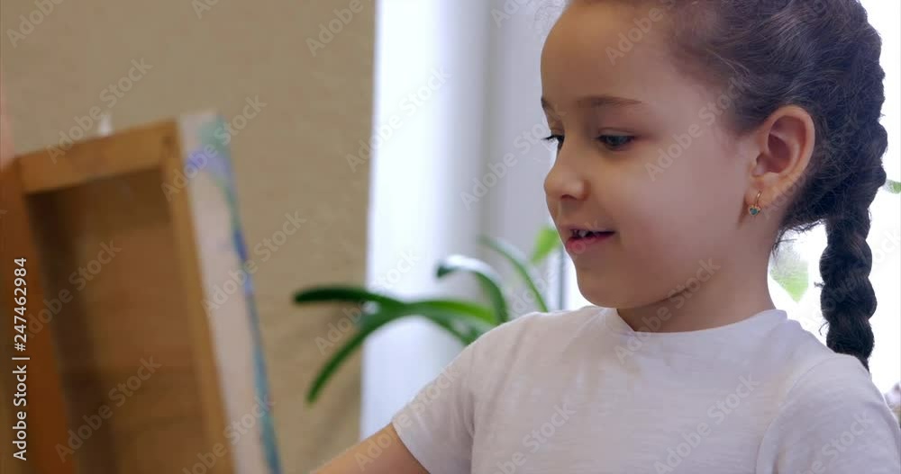 Young Hands of the Artist, Little Woman Artist Paints a Canvas with Brush,Sitting a Ttable and Draw on Canvas. Process of Drawing: in Artist's Art Studio Hand Girl Sketching on Canvas.Shot Close-up Young Hands of the Artist, Little Woman Artist Paints a Canvas with Brush,Sitting a Ttable and Draw on Canvas. Process of Drawing: in Artist's Art Studio Hand Girl Sketching on Canvas.Shot Close-up