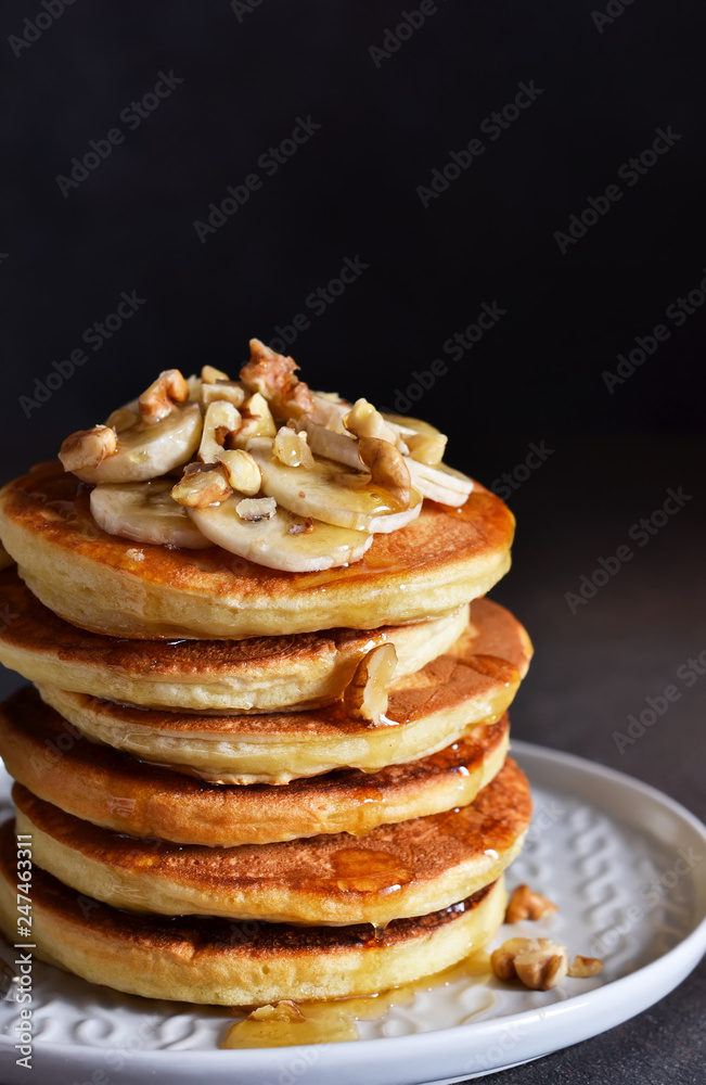 Homemade, hot pancakes with banana, honey and nuts on the kitchen table.