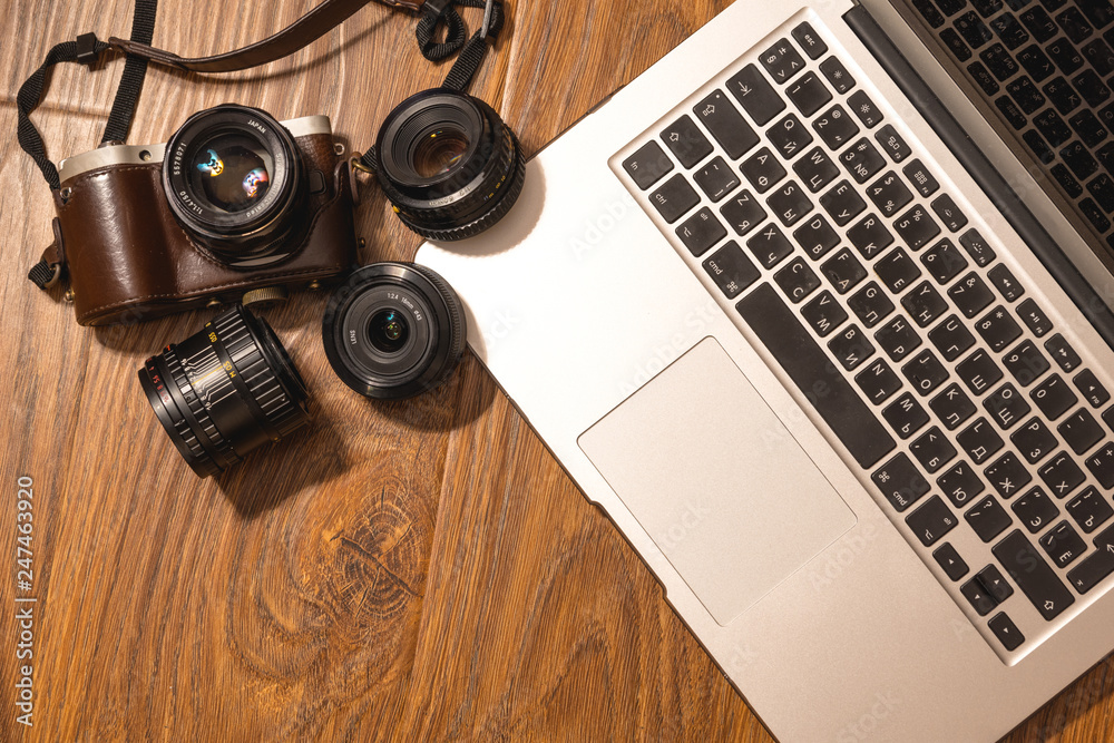 laptop and camera with lenses on wooden surface laptop and camera with lenses on wooden surface