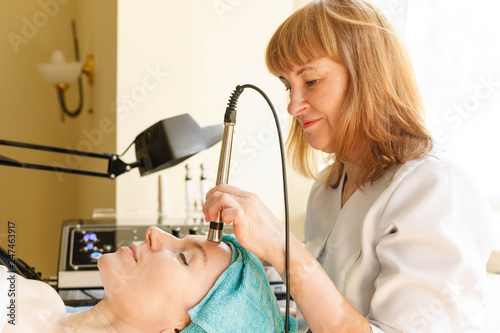 Cosmetologist makes the procedure microcurrent therapy in a beauty salon