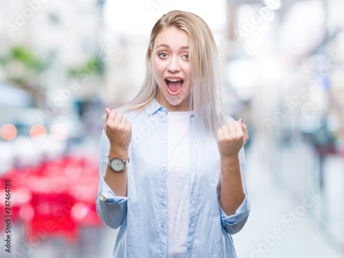 Young blonde woman over isolated background celebrating surprised and amazed for success with arms raised and open eyes. Winner concept.