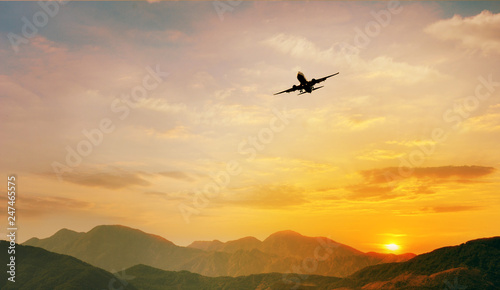 Airplane flying over the mountain at sunset