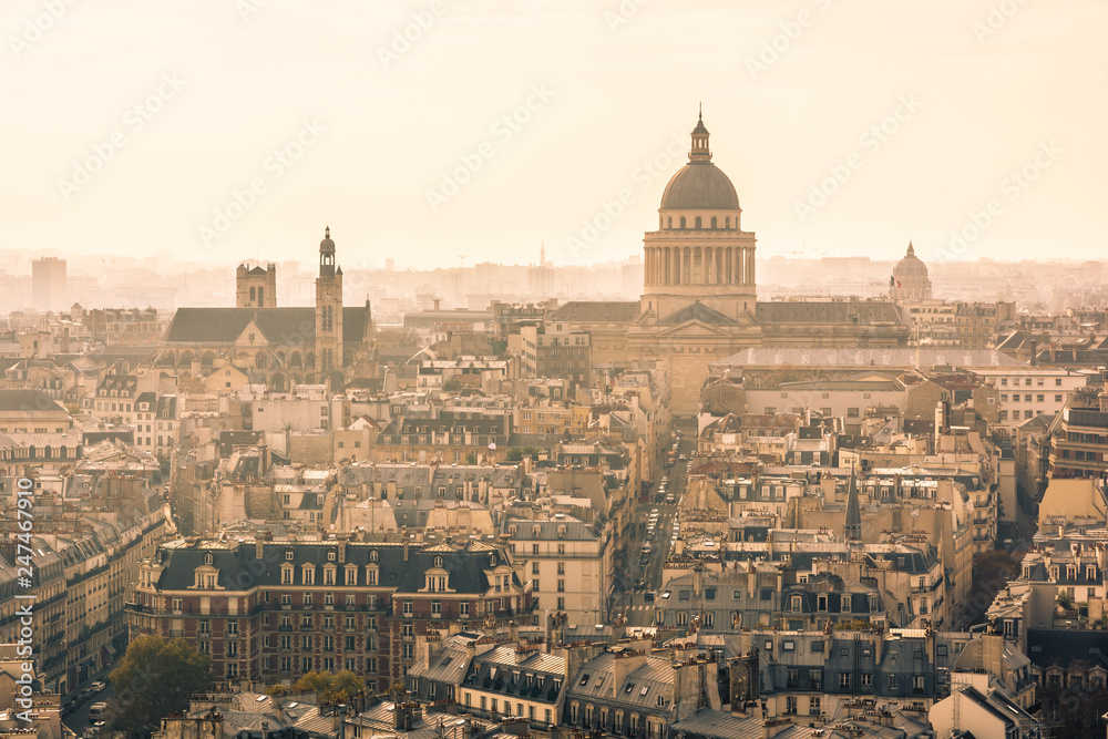 Aerial view of Paris, France, with the imposing cupola of the Pantheon overlooking the residential buildings in a sunny and misty atmosphere.