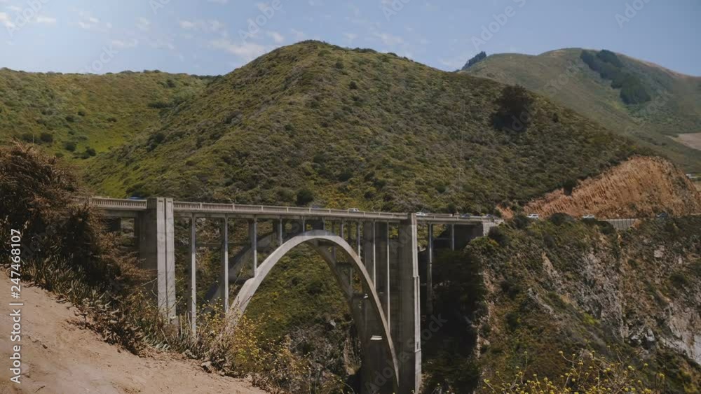 Atmospheric scenic wide shot of car traffic on iconic Bixby Canyon Bridge, Highway One in famous Big Sur California USA Atmospheric scenic wide shot of car traffic on iconic Bixby Canyon Bridge, Highway One in famous Big Sur California USA