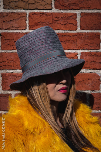 Undisclosed Korean woman in hat standing near an exposed brick wall photo