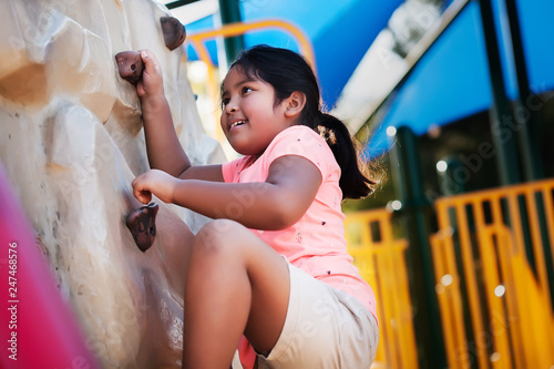 Young and physically active indian girl using her strength to conquer a rock climbing wall.