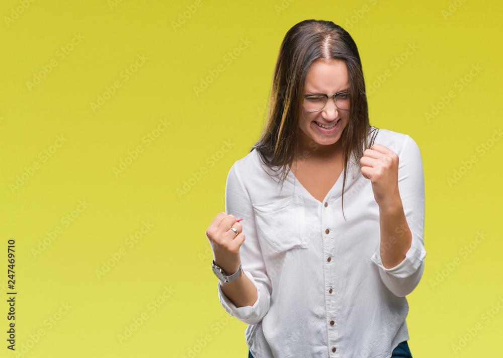 Young caucasian beautiful business woman wearing glasses over isolated background very happy and excited doing winner gesture with arms raised, smiling and screaming for success. Celebration concept. Young caucasian beautiful business woman wearing glasses over isolated background very happy and excited doing winner gesture with arms raised, smiling and screaming for success. Celebration concept.