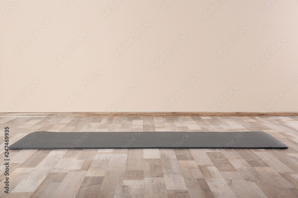 Fototapeta premium Grey yoga mat on floor indoors. Space for text