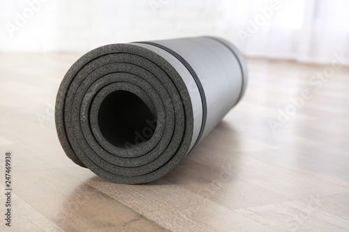 Rolled grey yoga mat on floor indoors