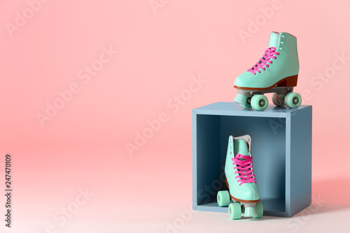 Pair of vintage roller skates and storage cube on color background. Space for text