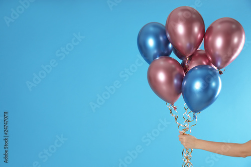 Woman holding bunch of balloons on color background, closeup. Space for text