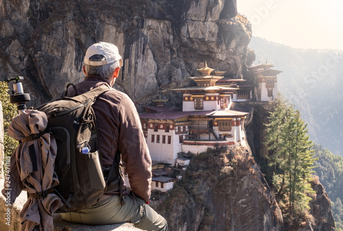 tourist sitting on his back watching tiger`s nest temple in Paro, Bhutan photo