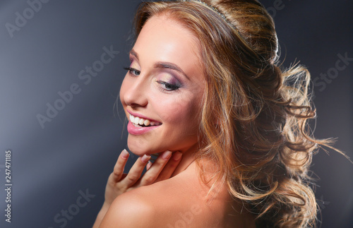 Beautiful woman with curly long hair on dark background .
