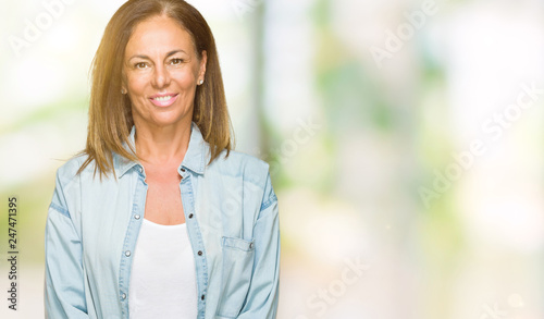 Middle age adult woman wearing casual denim shirt over isolated background with a happy and cool smile on face. Lucky person.