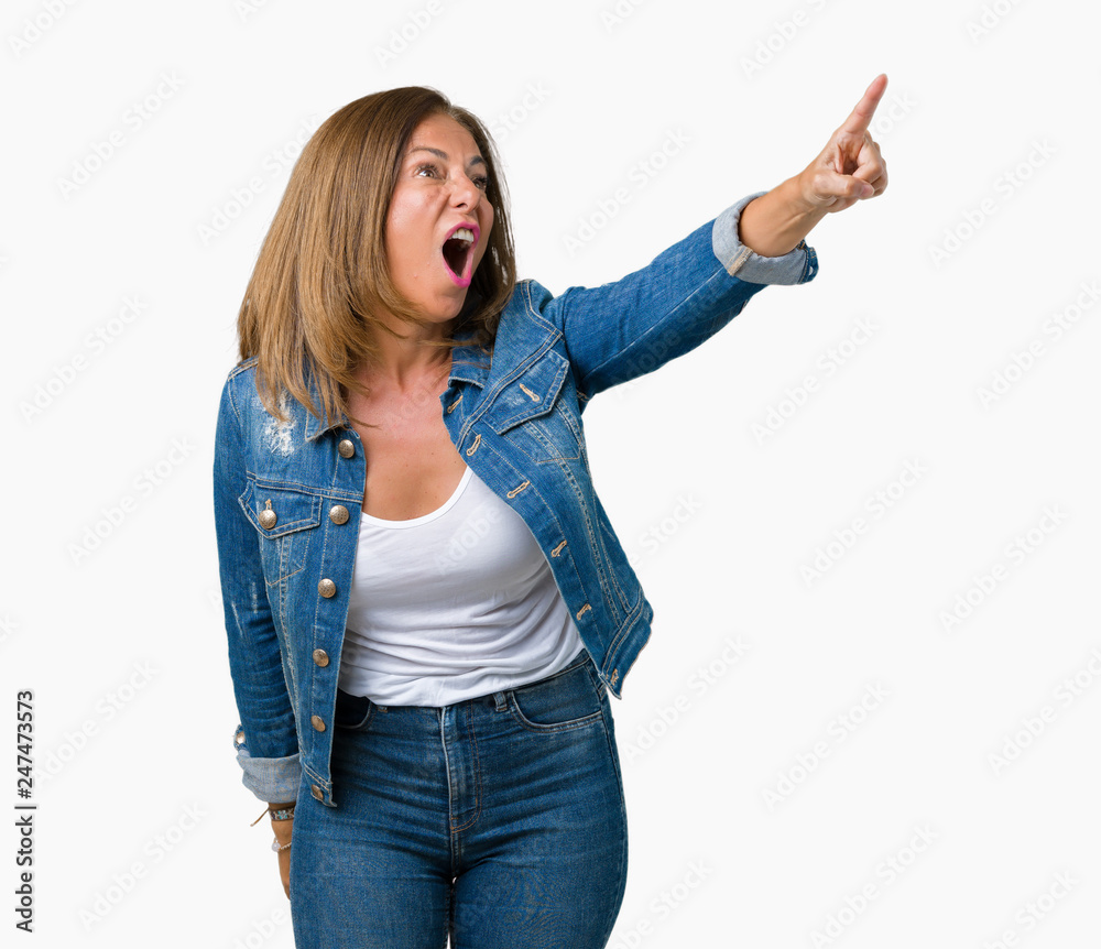 Beautiful middle age woman wearing casual denim jacket over isolated background Pointing with finger surprised ahead, open mouth amazed expression, something in front Beautiful middle age woman wearing casual denim jacket over isolated background Pointing with finger surprised ahead, open mouth amazed expression, something in front
