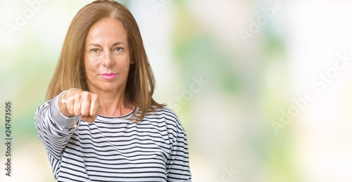 Beautiful middle age woman wearing stripes sweater over isolated background Punching fist to fight, aggressive and angry attack, threat and violence