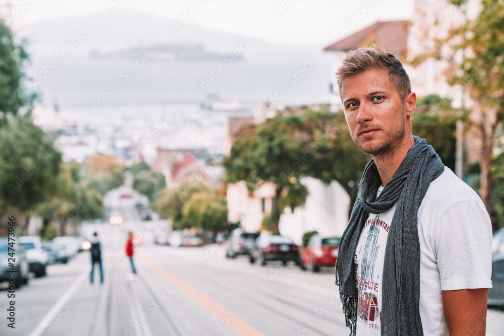 Φωτογραφία Young man exploring San Francisco city near the traditional cable car tram and Alcatraz island on the background
