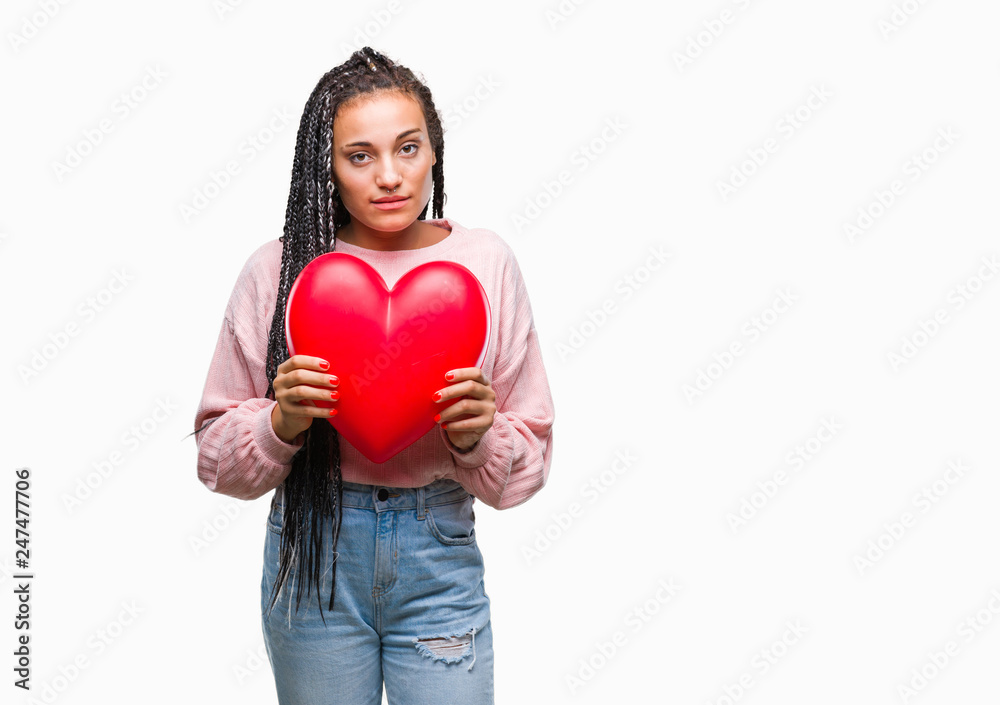 Young braided hair african american girl holding read heart over isolated background with a confident expression on smart face thinking serious Young braided hair african american girl holding read heart over isolated background with a confident expression on smart face thinking serious