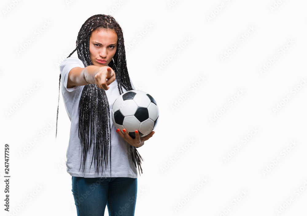 Young braided hair african american girl holding soccer ball over isolated background pointing with finger to the camera and to you, hand sign, positive and confident gesture from the front Young braided hair african american girl holding soccer ball over isolated background pointing with finger to the camera and to you, hand sign, positive and confident gesture from the front