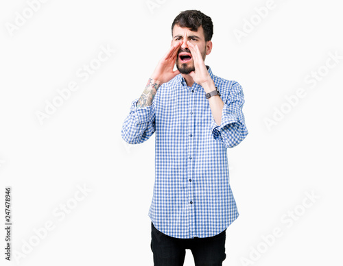 Young handsome business man over isolated background Shouting angry out loud with hands over mouth