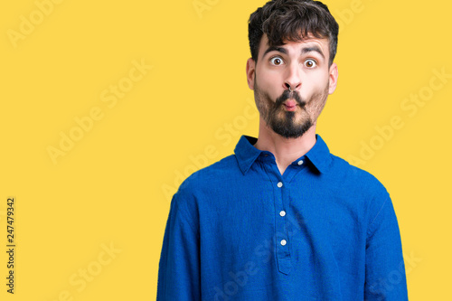 Young handsome man over isolated background making fish face with lips, crazy and comical gesture. Funny expression.