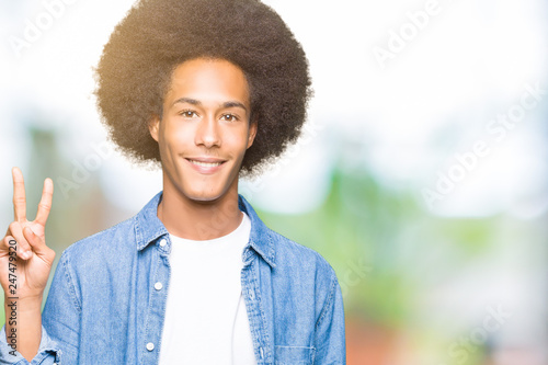 Young african american man with afro hair showing and pointing up with fingers number two while smiling confident and happy.