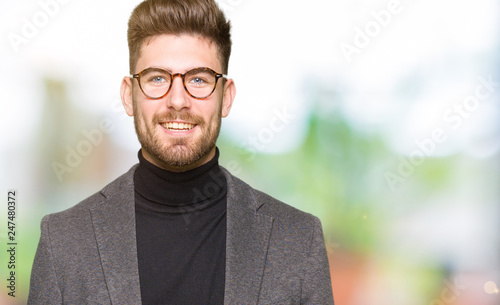 Young handsome business man wearing glasses with a happy and cool smile on face. Lucky person.