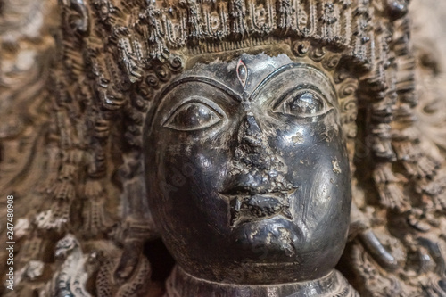 Halebidu, Karnataka, India - November 2, 2013: Hoysaleswara Temple of Shiva. Closeup of damaged Dwarapalaka face at entrance to Mandapam of main temple building. Gray brown stone. 