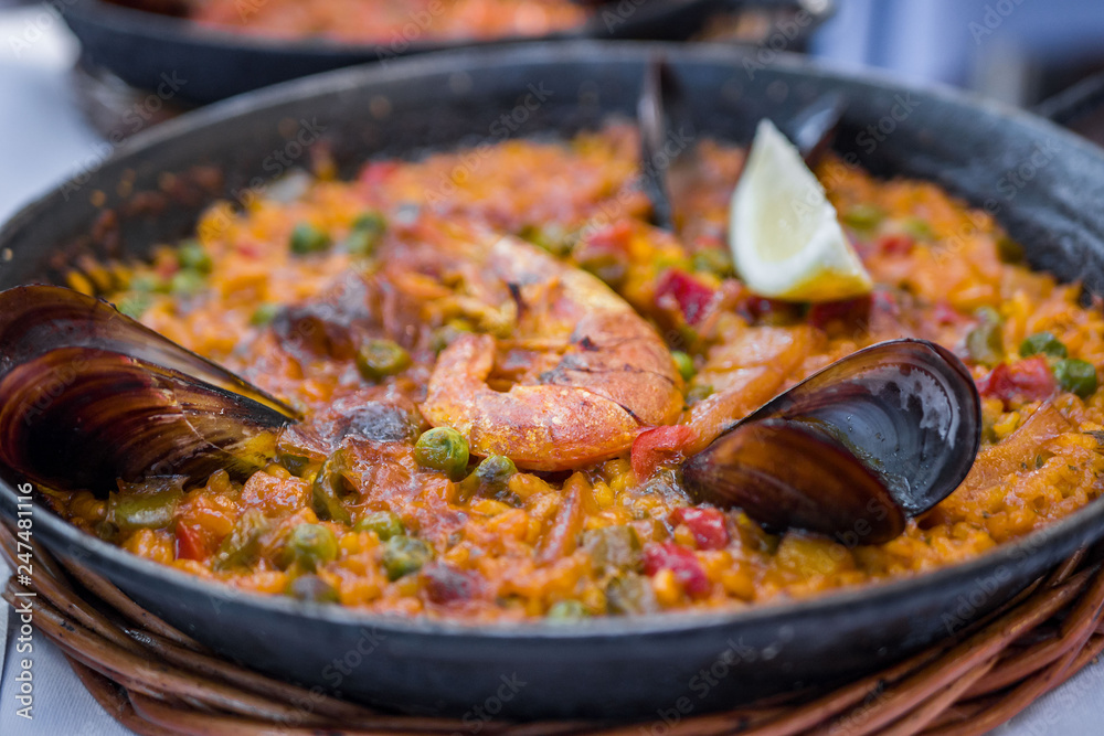 Delicious seafood paella on an iron pan. Rice, lemon, mussels, shrimp and vegetables