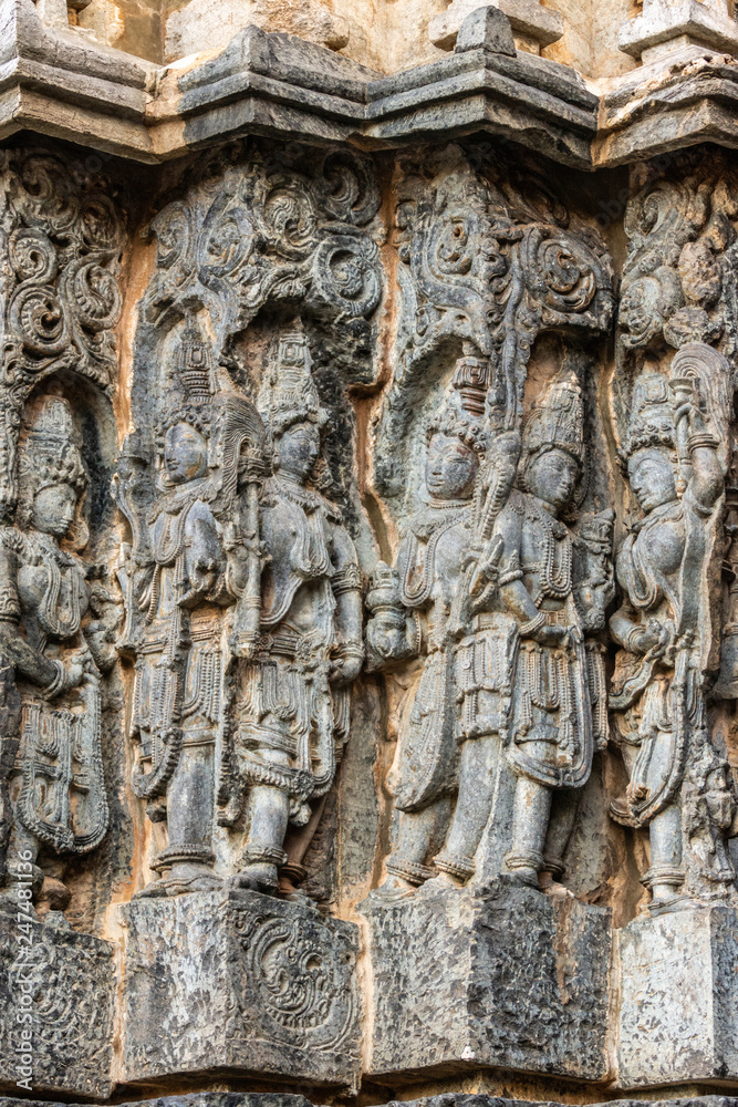 Halebidu, Karnataka, India - November 2, 2013: Hoysaleswara Temple of Shiva. Series of corner statues on side of the temple structure in gray stone and some brown background.